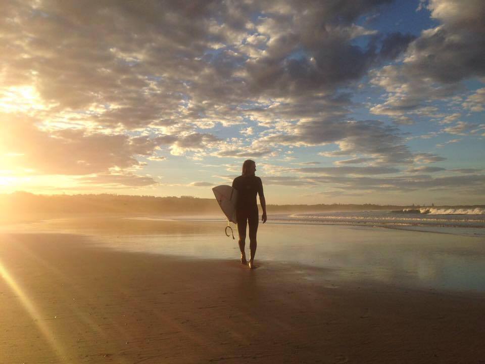 Surfer bei Sonnenaufgang am Strand in Byron Bay, Australien